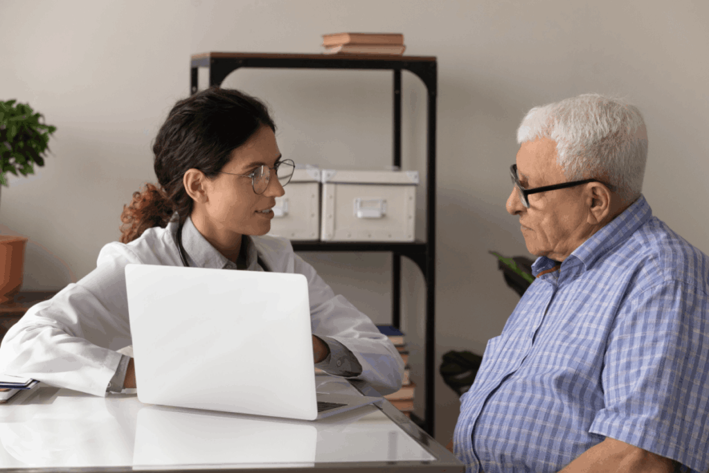  A young doctor reviews an electronic health record on a laptop with an older patient. 
